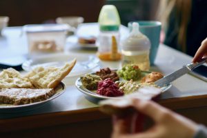 Ein Teller mit veganen Pasten, im Hintergrund stehen zwei Babytrinkflaschen auf dem Tisch.